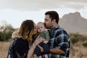 A tender family moment captured against a mountain backdrop at sunset.