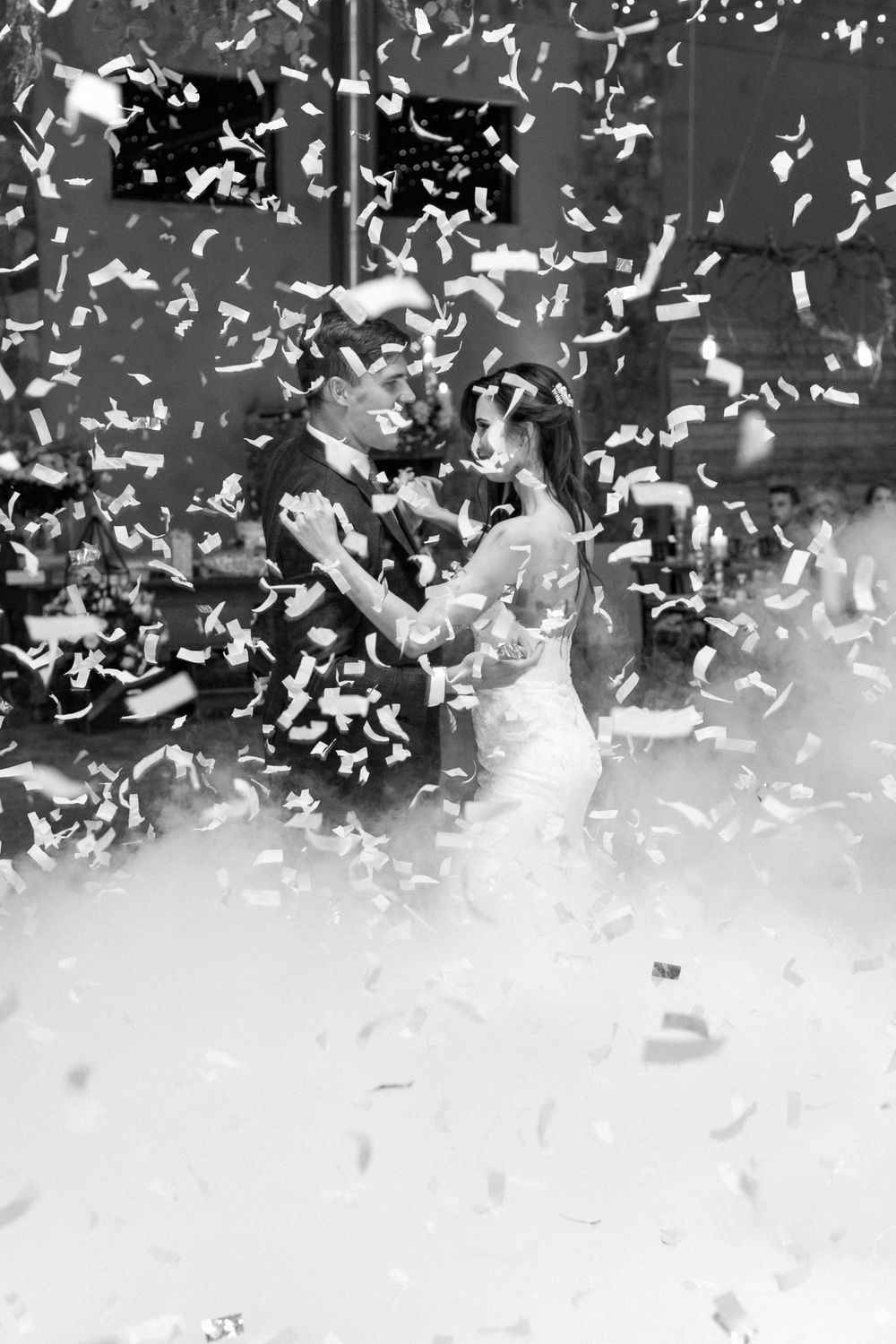 A couple dancing their first dance with confetti raining down on them.