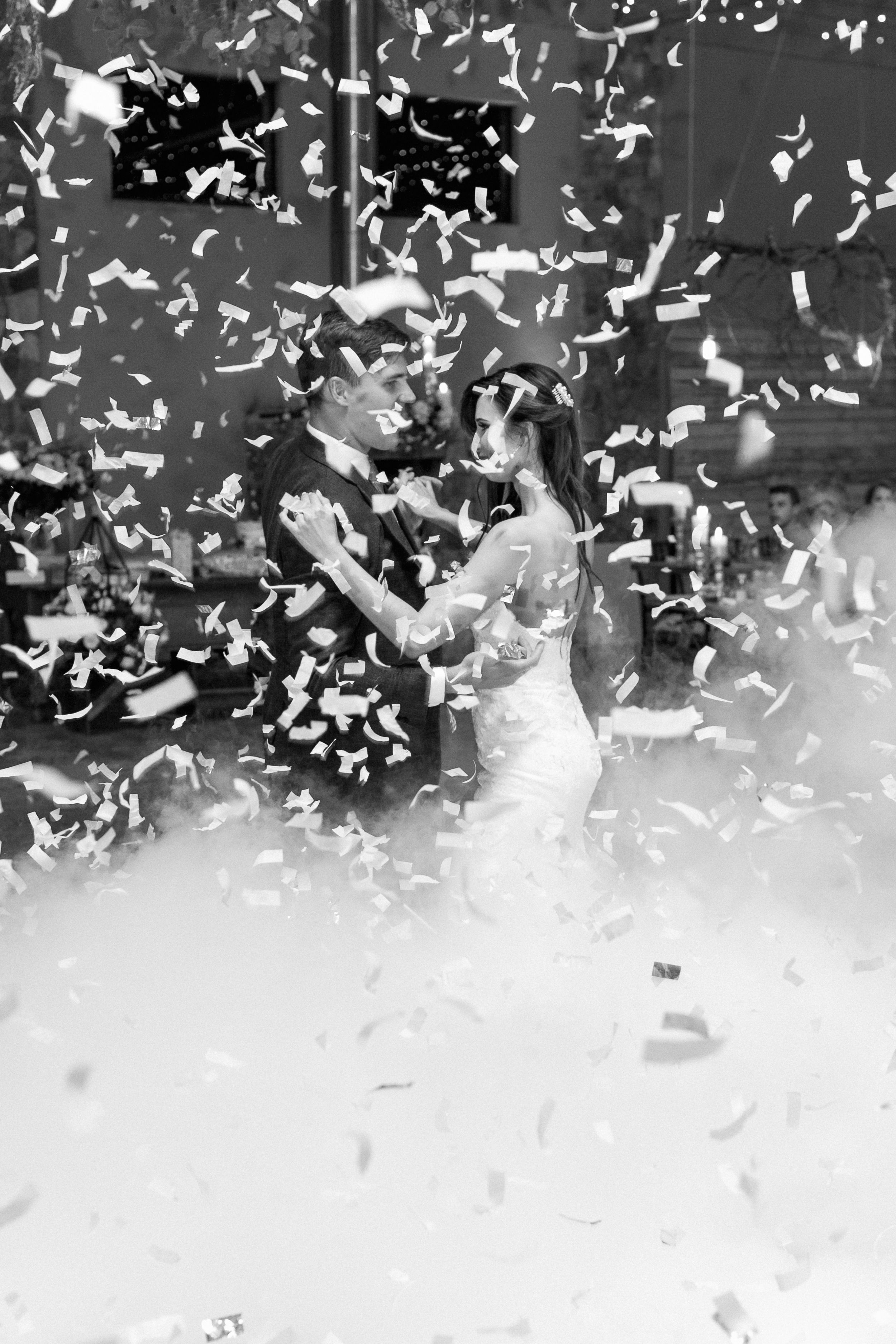 A couple dancing their first dance with confetti raining down on them.