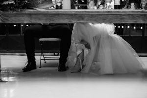 A bride and groom's shoes peeking out from underneath their dinner table.