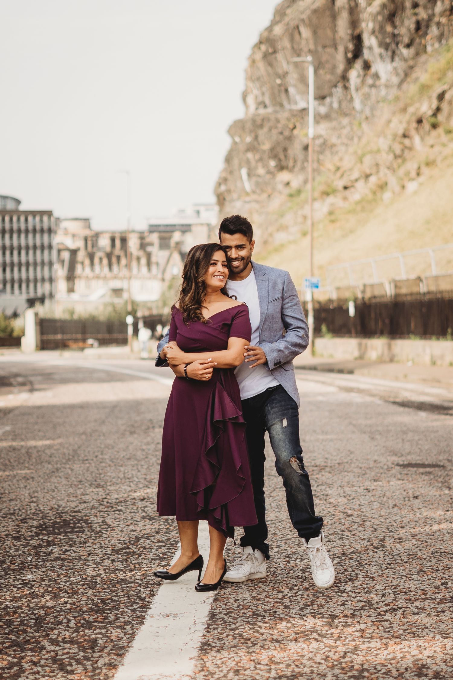 Stylish couple sharing intimate moment on urban street with mountain backdrop.