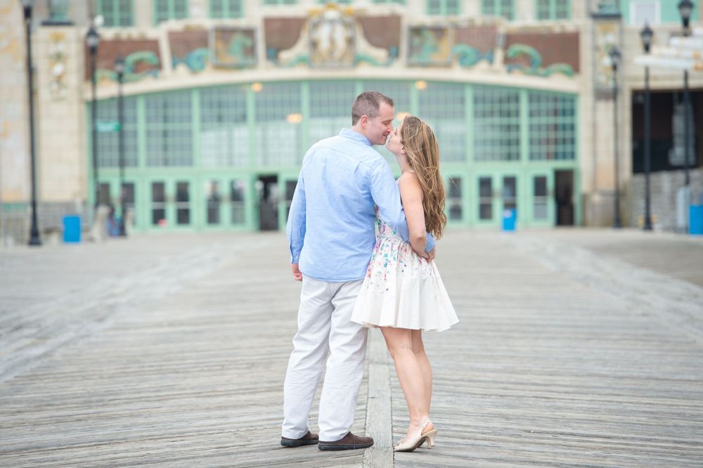 Couple walking along wooden boardwalk near historic convention center building.