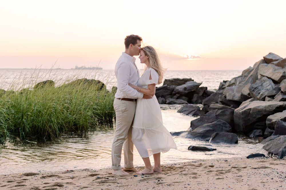 Romantic beach photoshoot with waves crashing on rocks during golden hour.