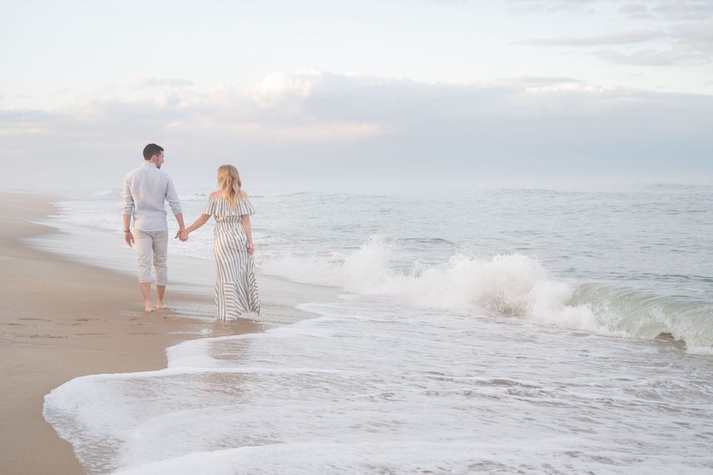 Romantic beach photoshoot with waves crashing on shore at sunset.