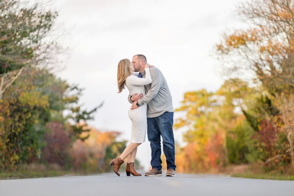 Playful couple interaction during fall photoshoot with golden leaves in background.
