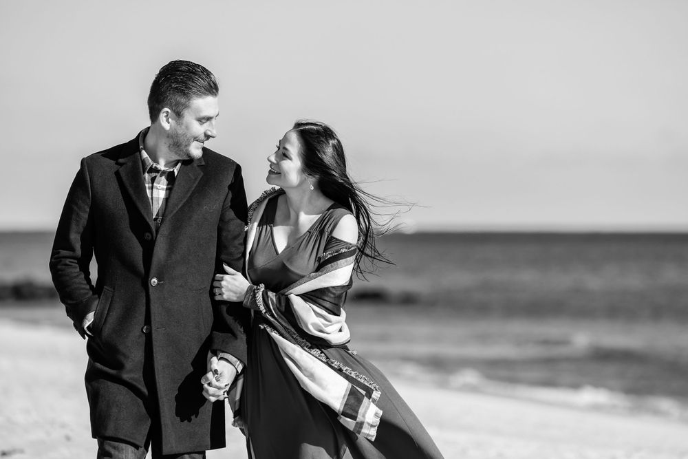 Black and white candid moments of couple laughing together by the ocean.