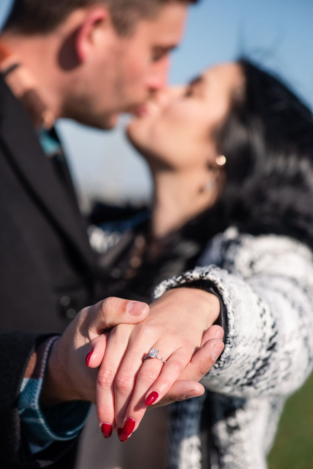 Close up of hands showing engagement ring with red nail polish.