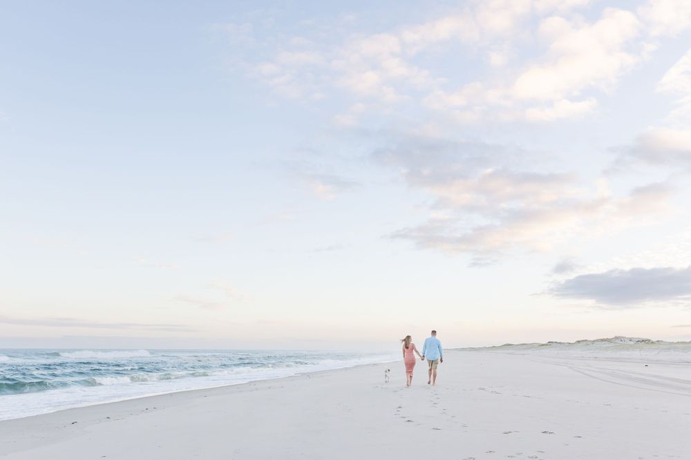 Scenic coastal landscape with sand dunes and ocean waves under cloudy skies.