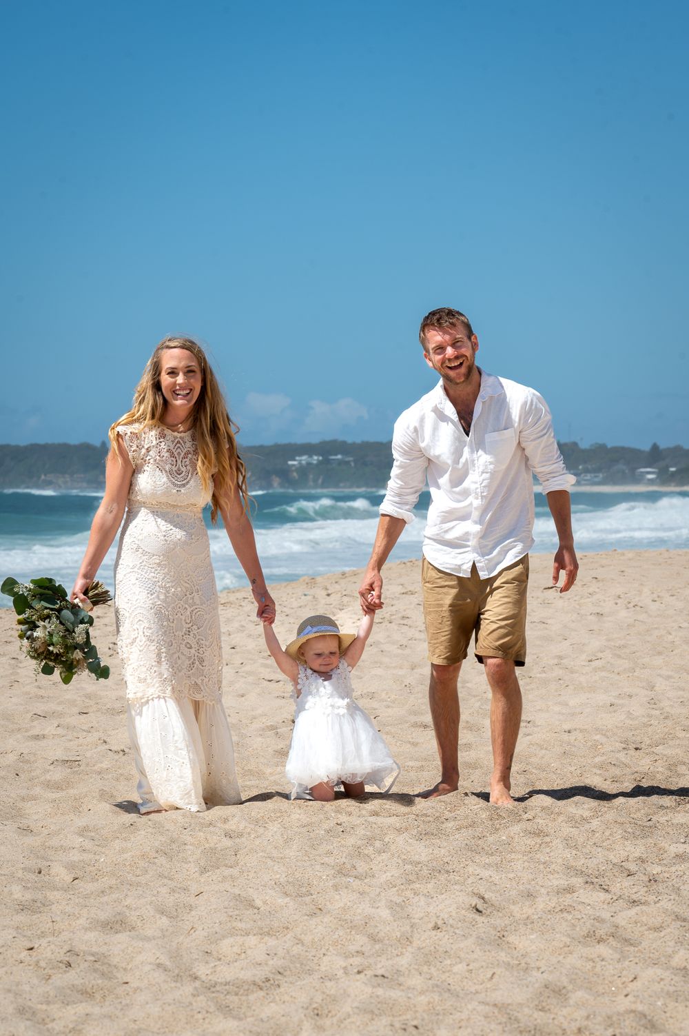 Husband, Wife and Daughter - flower girl walking on the sandy beach