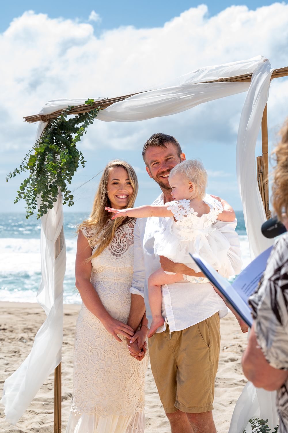The celebrant talking to the Husband and Wife while they hold their daughter in their arms