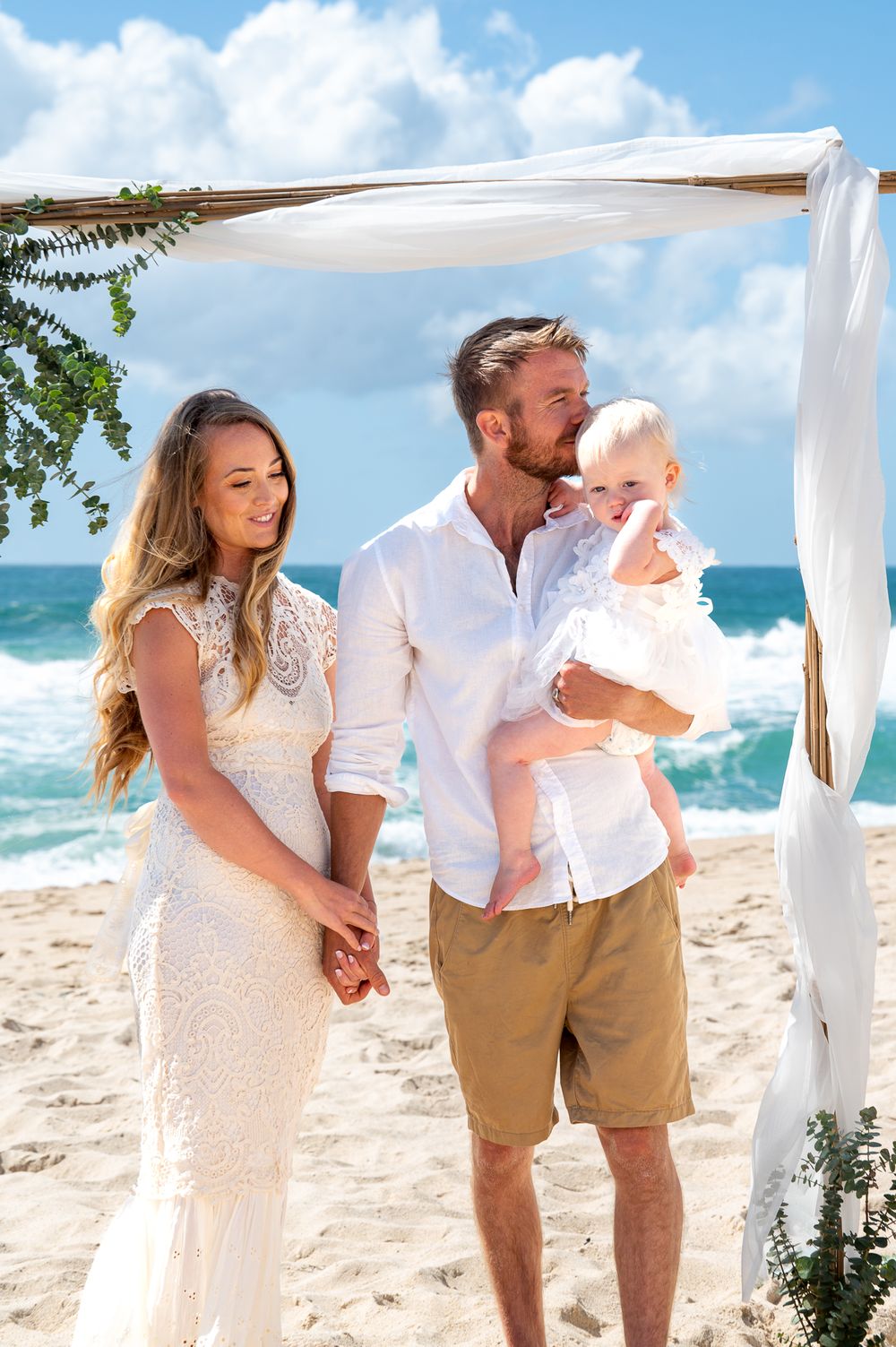 Husband and Wife holding their flower girl while getting married