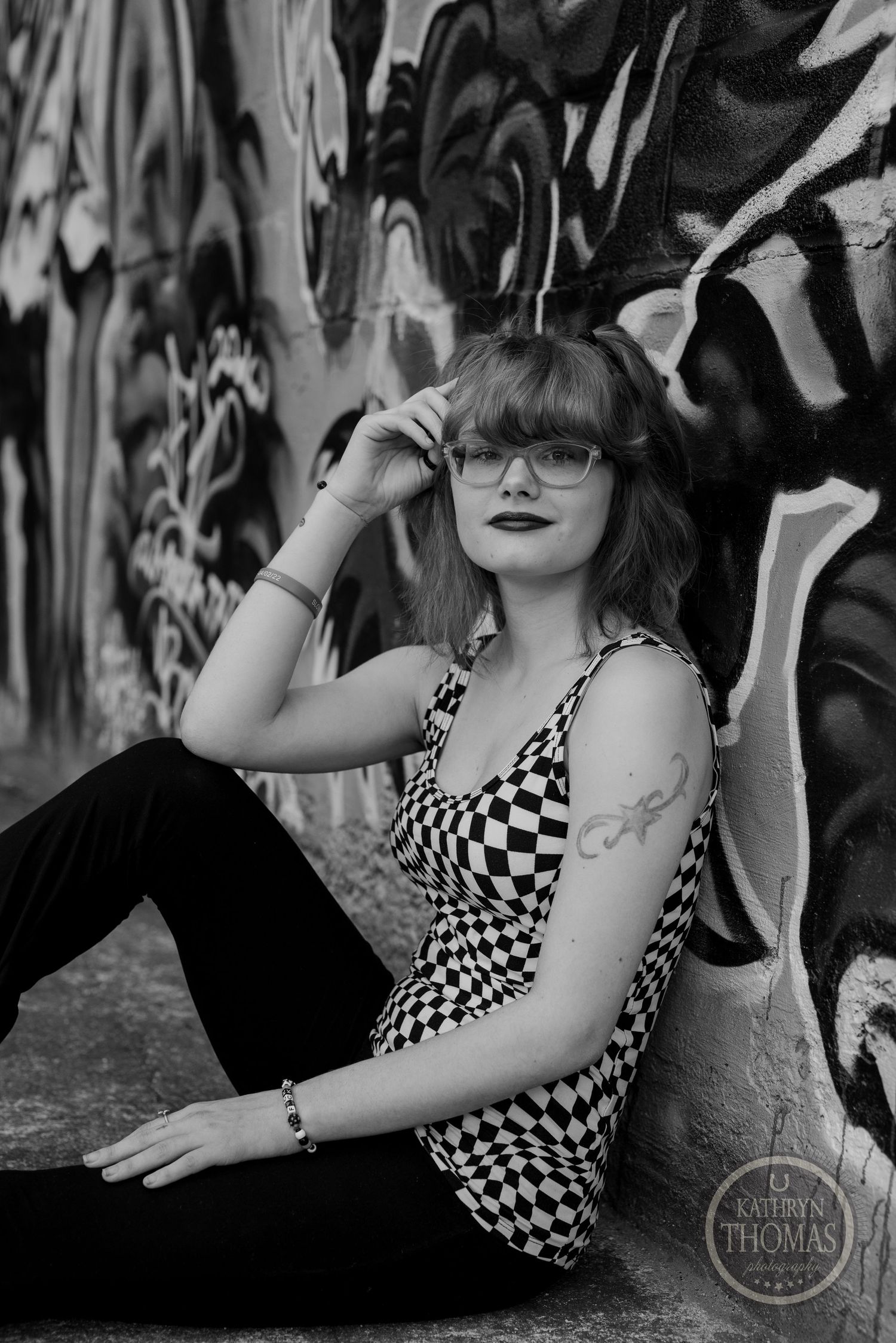 A retro-inspired fashion shoot featuring black and white checkered top against graffiti wall background with artistic lighting.