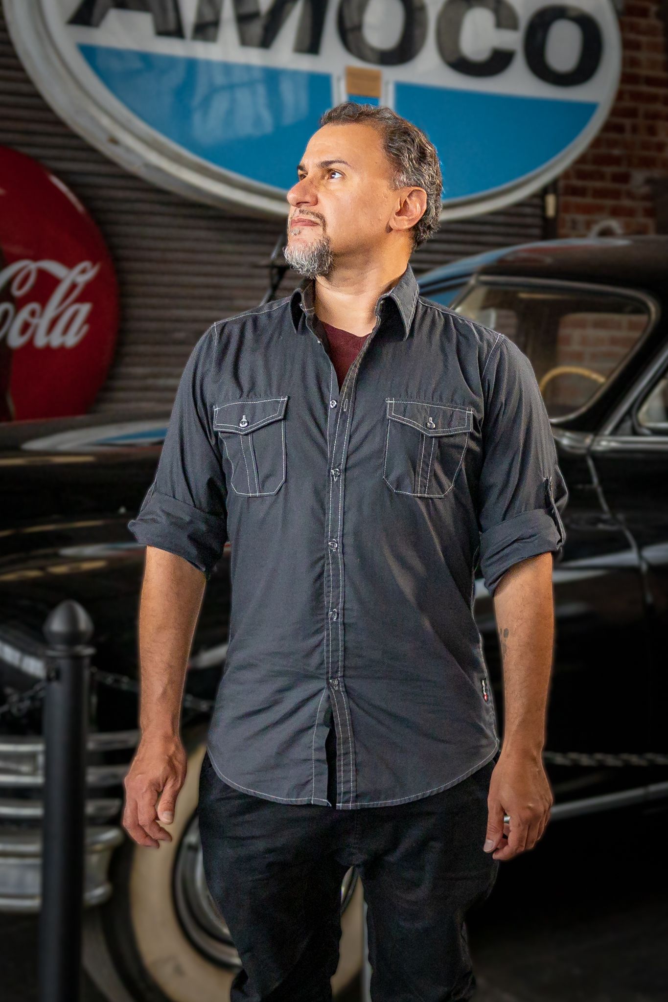 Portrait of a dapper man posing confidently in front of a vintage car.