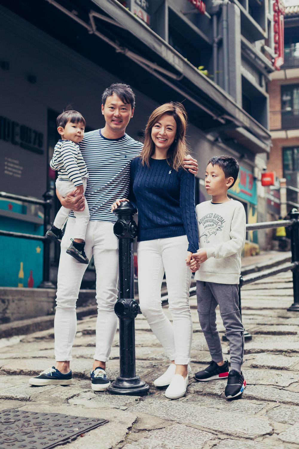 A family stands together on cobblestone streets in an urban setting with historical buildings.