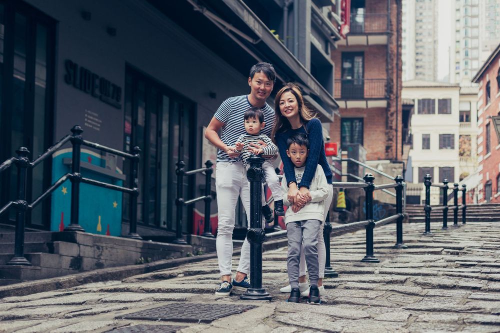 A family photo on a historic cobblestone street with traditional architecture in the background.