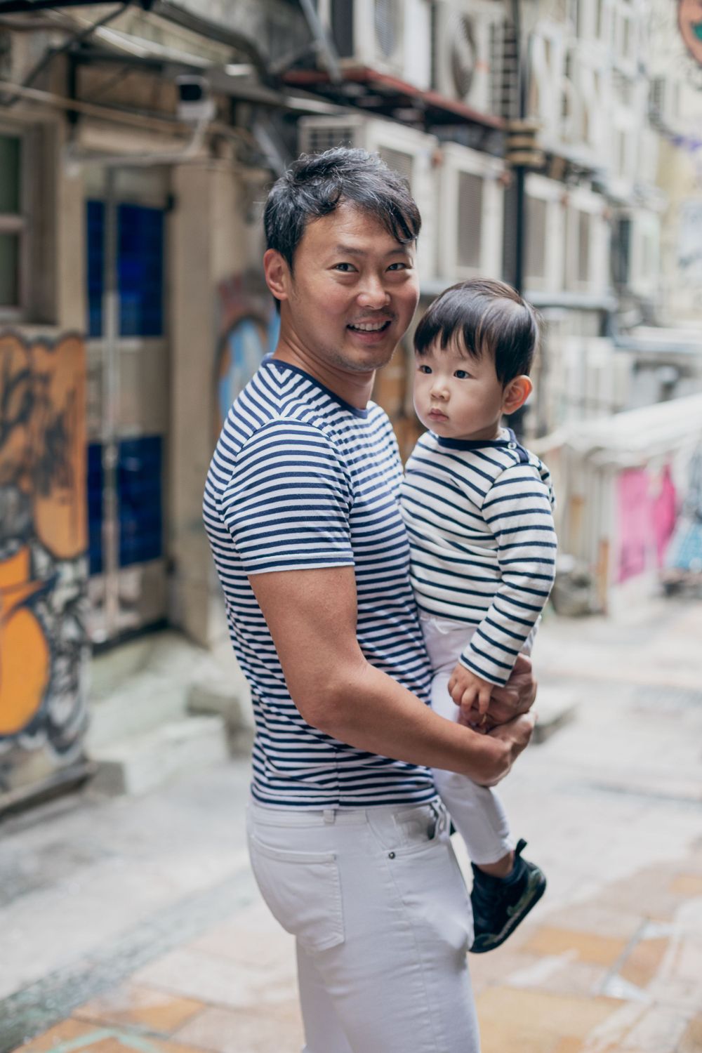 Matching striped shirts worn in a candid moment on a city alley.