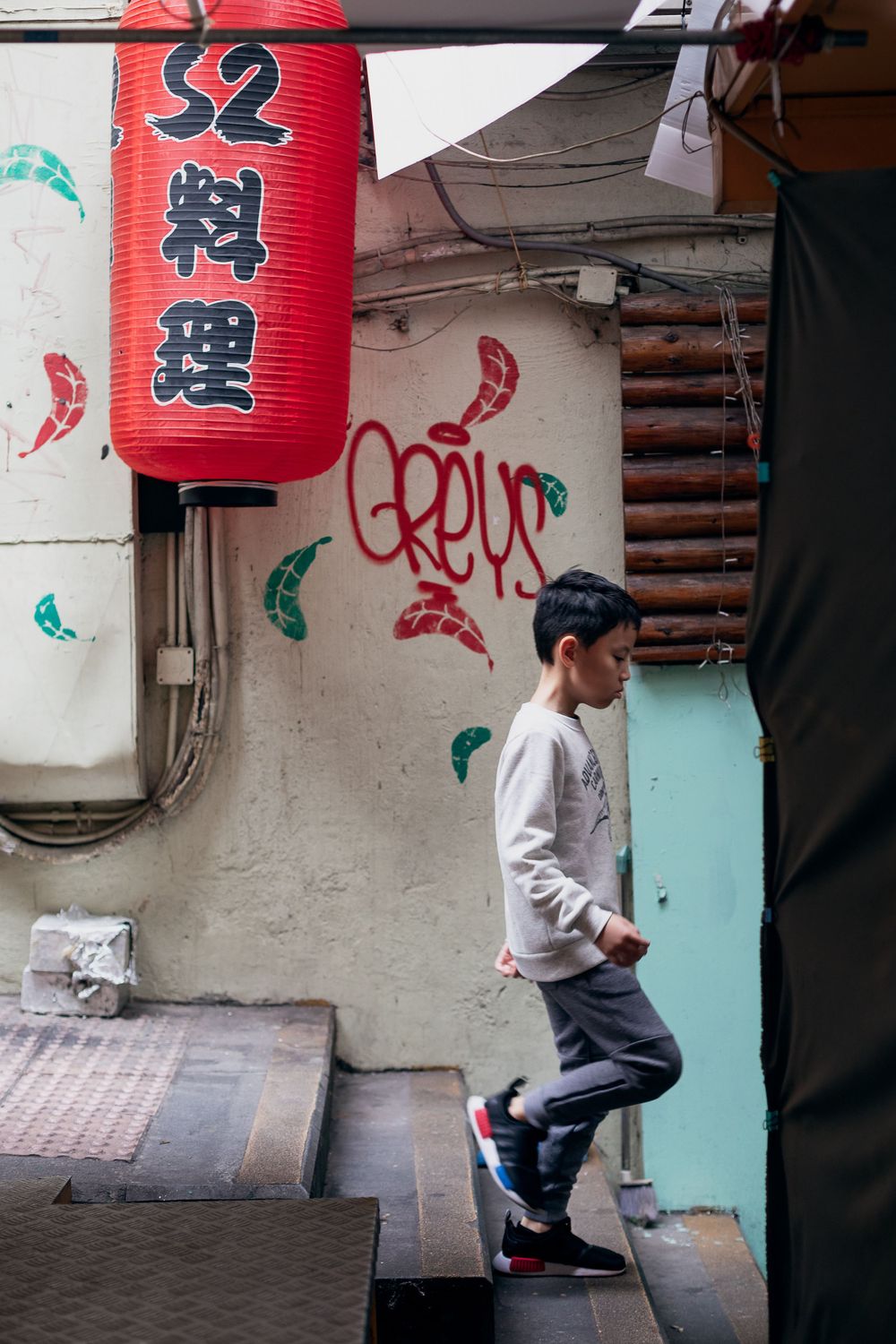 A series of red paper lanterns hanging above a street entrance with Asian characters.