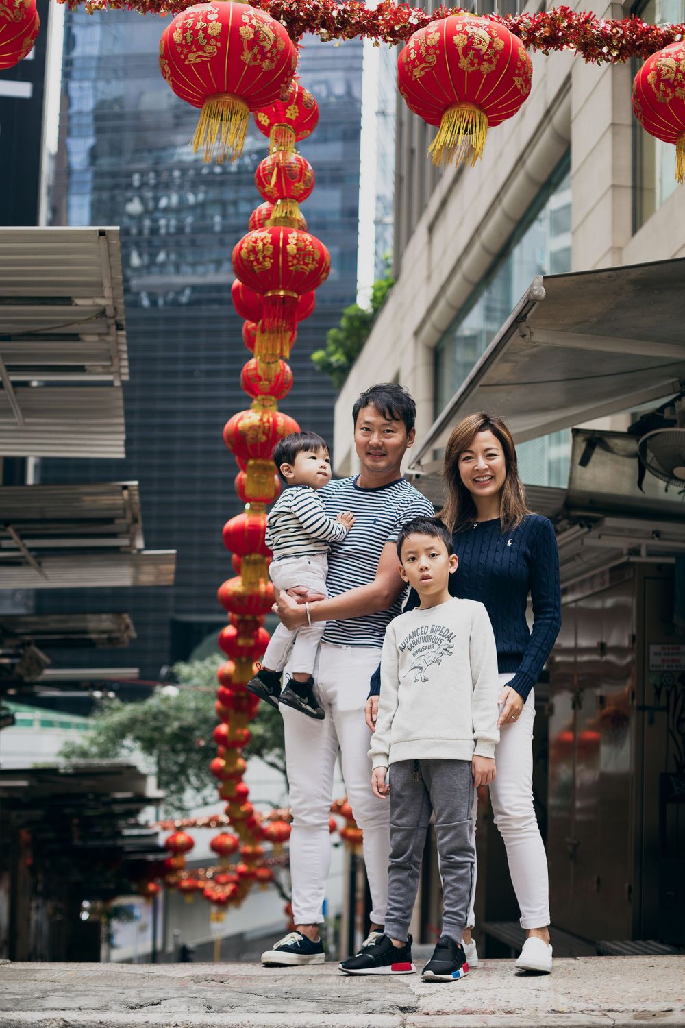 Family portrait session under festive red lanterns in a Chinese shopping area.