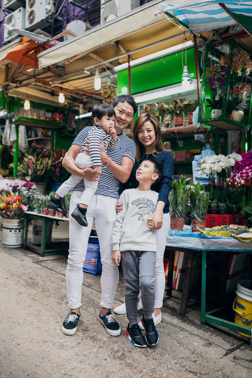 Family enjoying a moment together at a local flower market with colorful displays.
