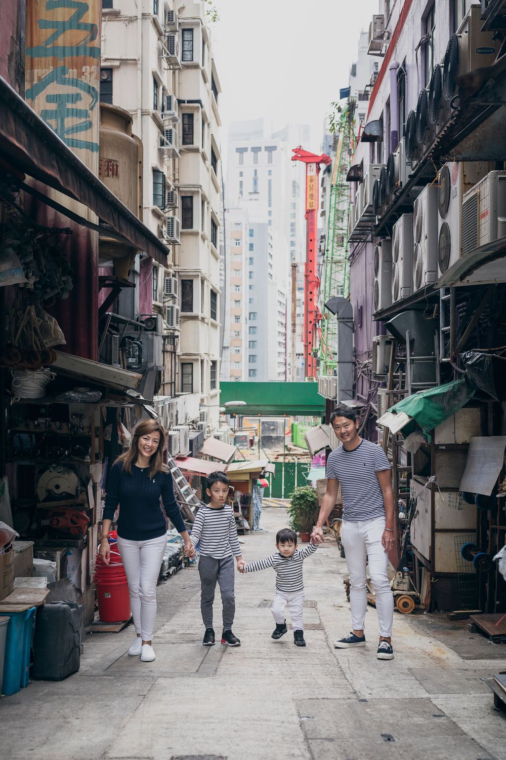 Family walking together down a narrow urban alley in Hong Kong.
