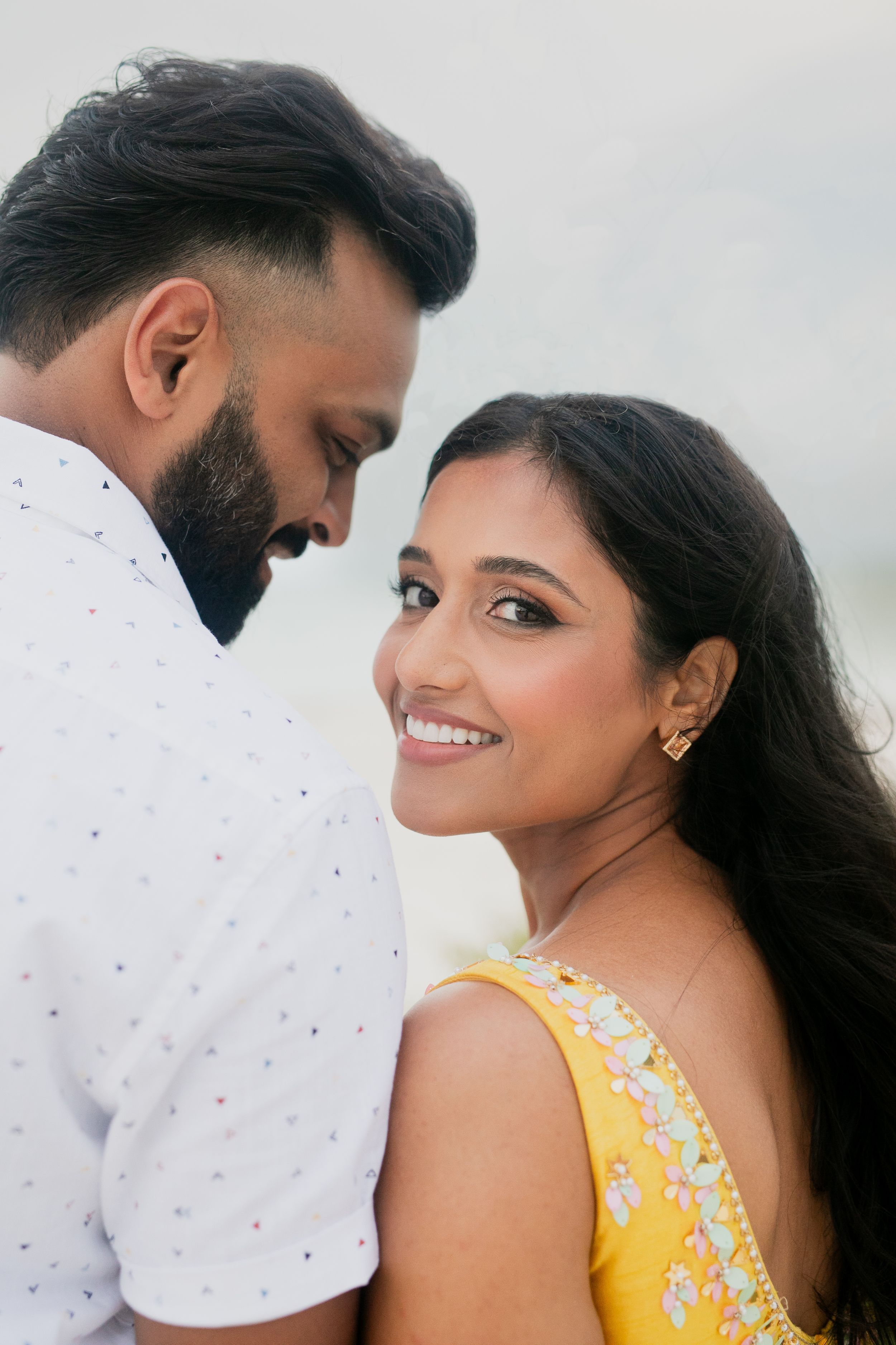 A close-up portrait of a couple with one wearing a bright yellow dress.