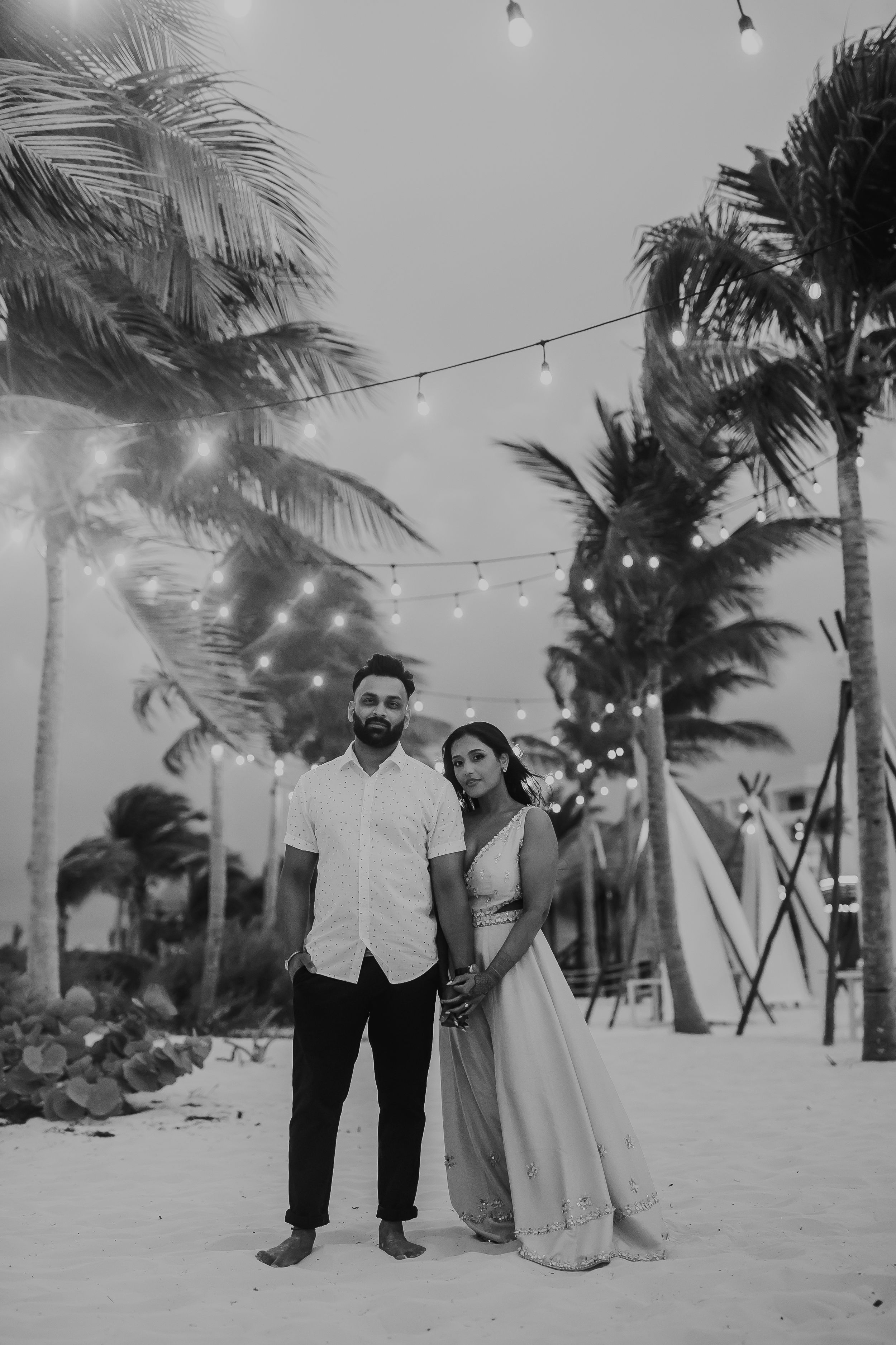 A romantic beachside scene with string lights, palm trees, and flowing dresses in the evening breeze.