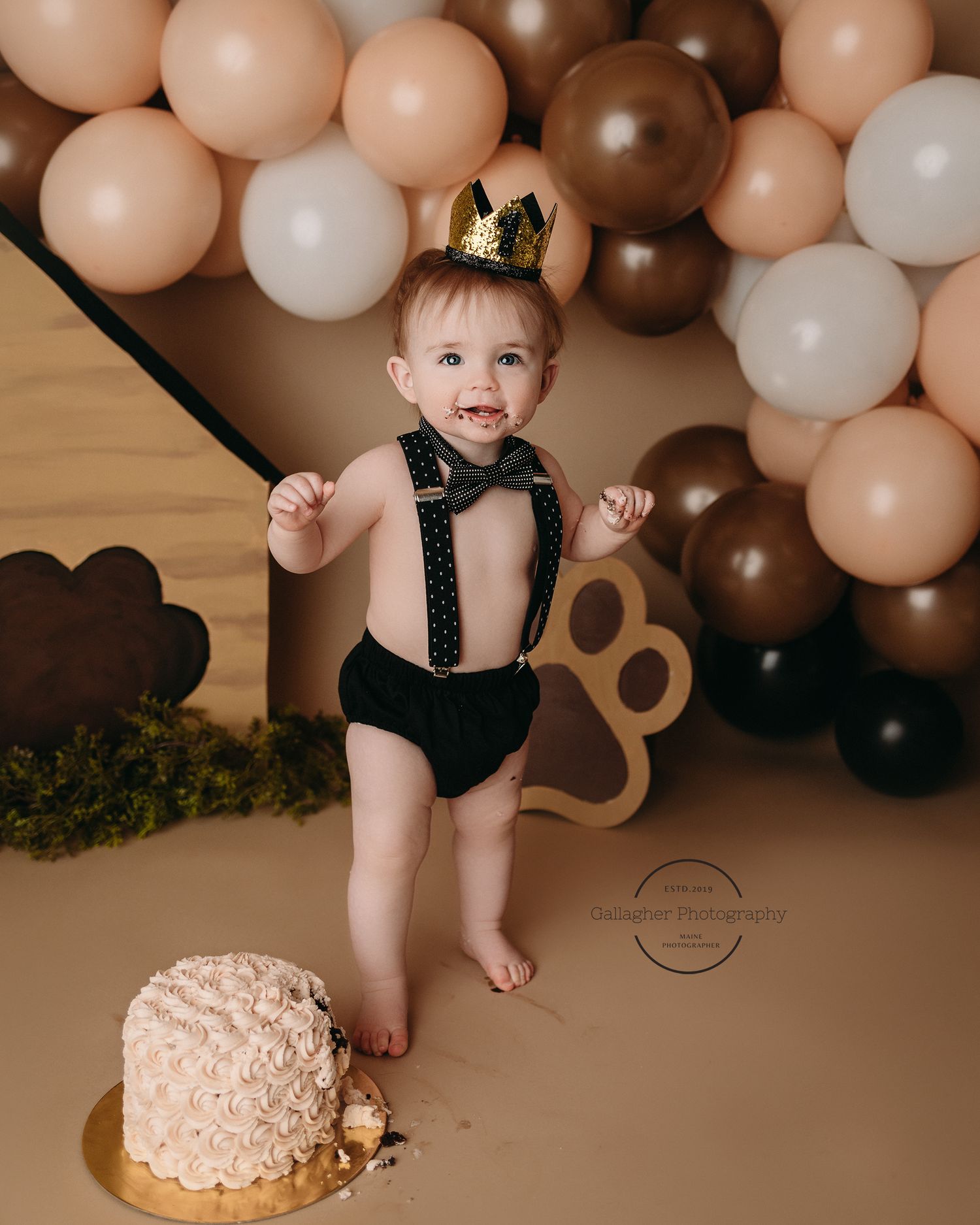 Professional photo of a baby in suspenders with a birthday cake