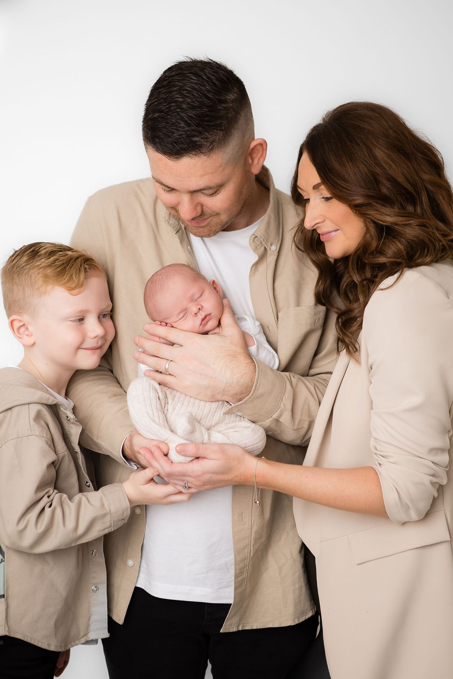Intimate family portrait in neutral tones against white background.