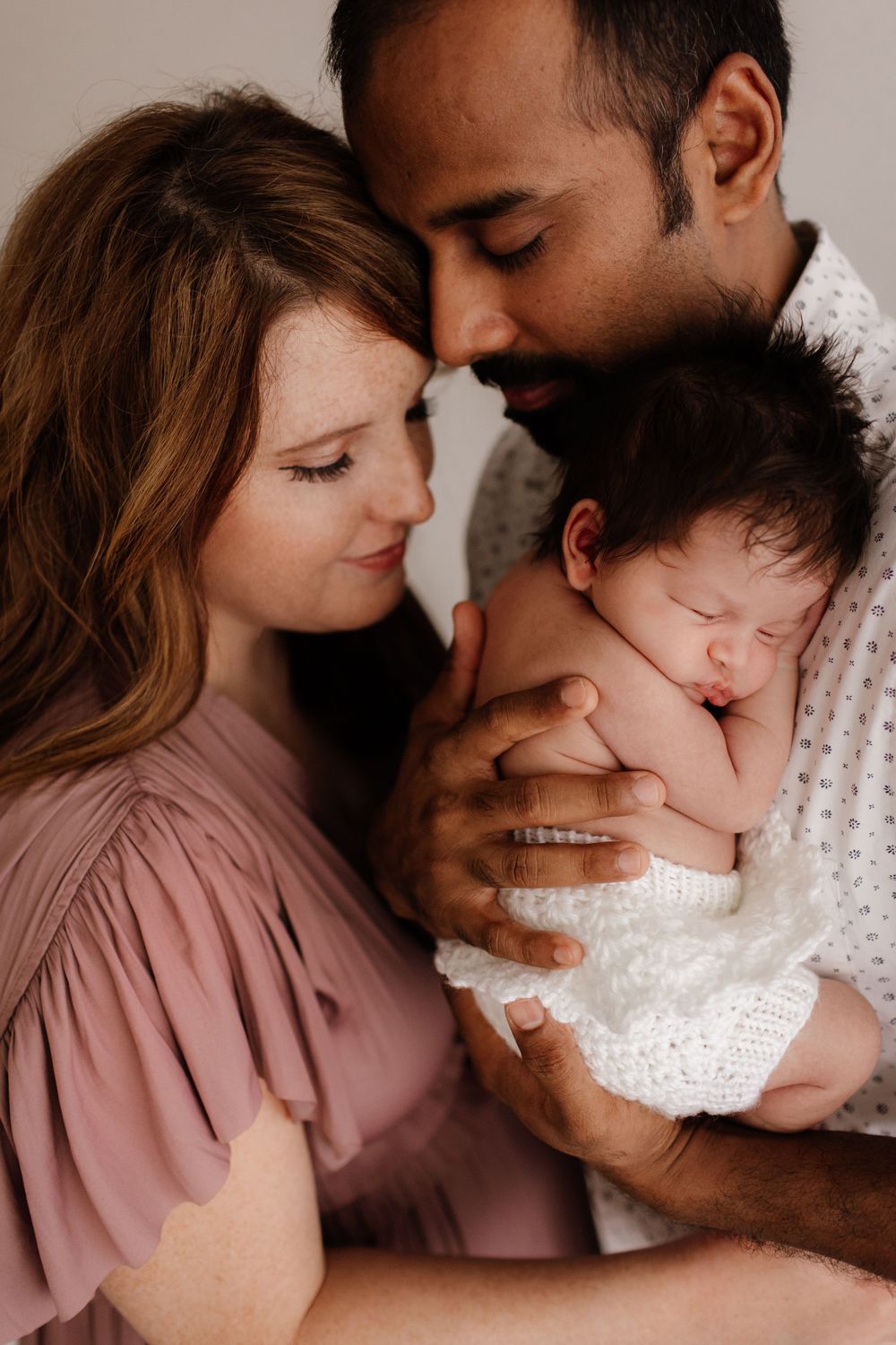 Father, Mother and newborn photo with father cuddling infant and mother snuggled in close. Studio newborn photography by Jen Roberts
