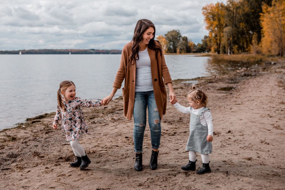 Family walking along autumn beach shoreline during photo session.