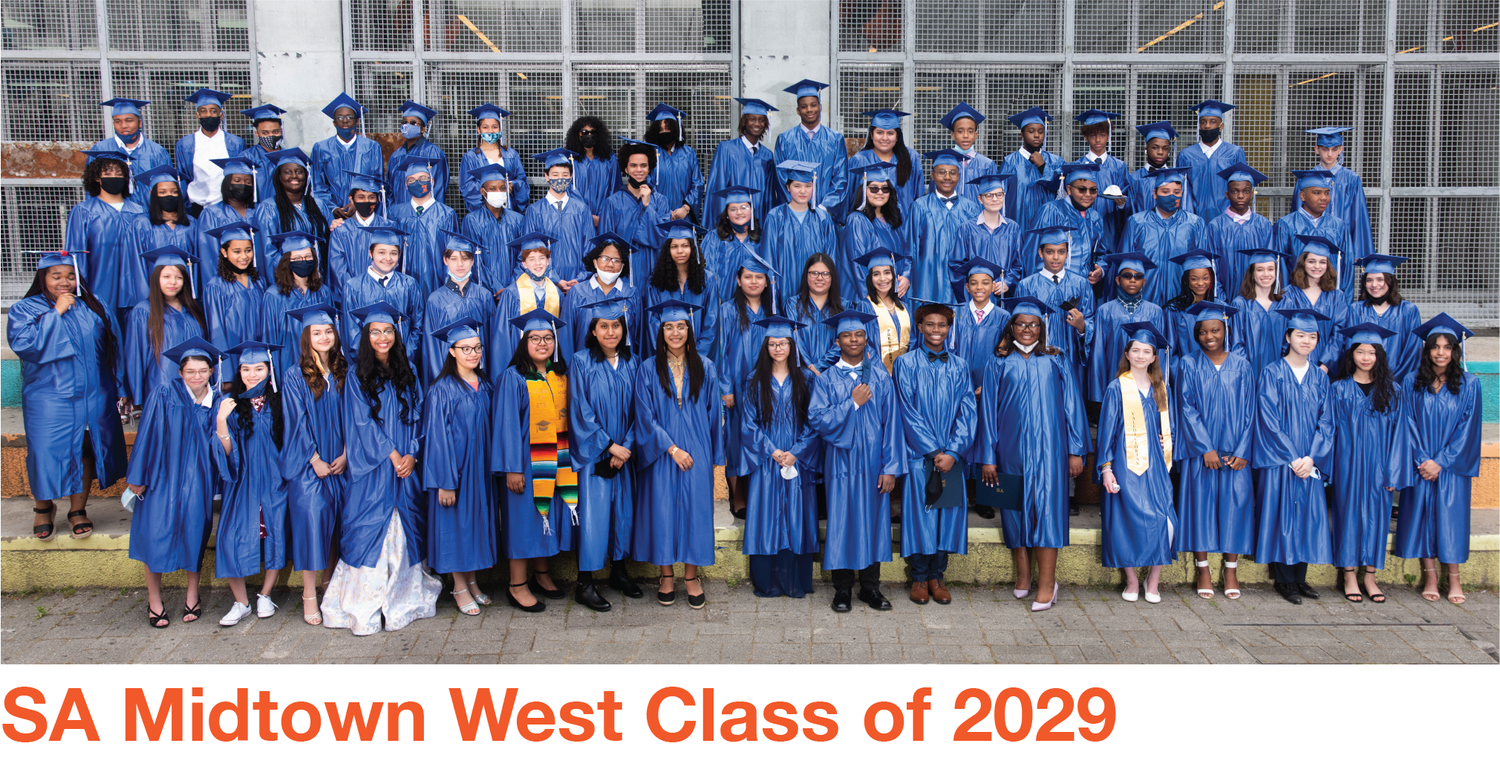 Large group of graduates in blue caps and gowns posing for class photo.