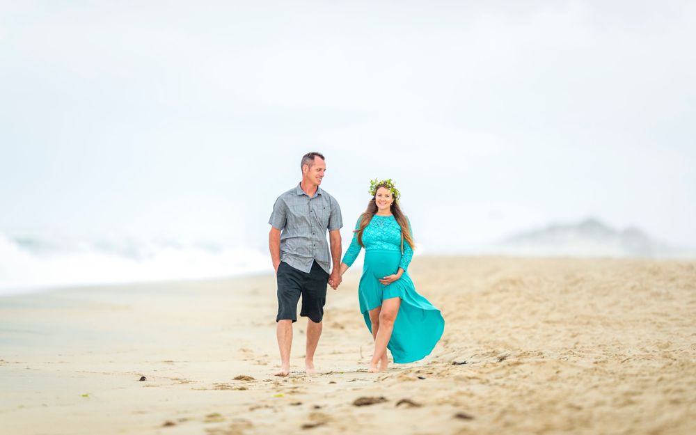 Expecting parents walking on beach holding hands