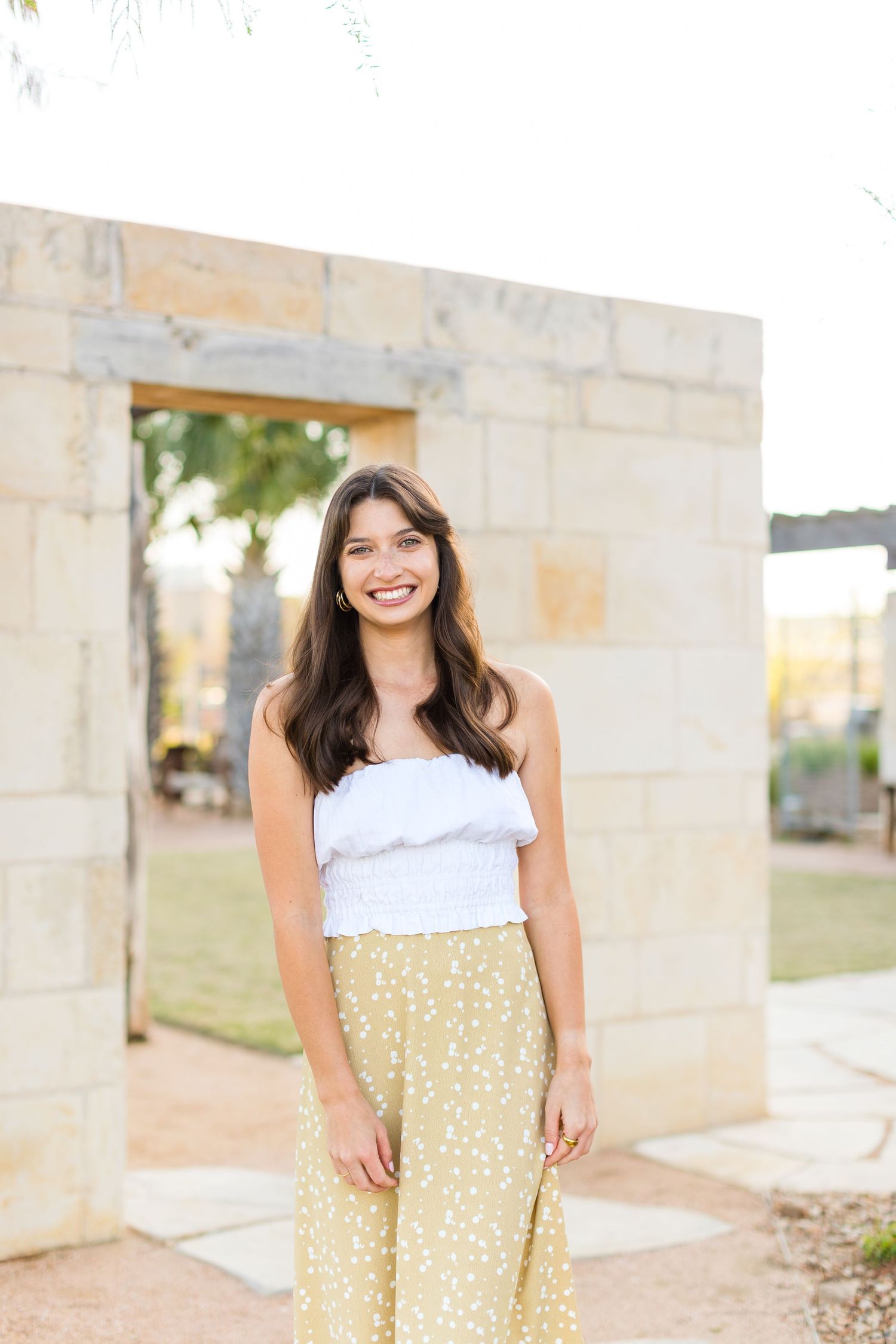 Casual summer portrait in front of stone wall with warm natural lighting.