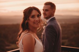 A romantic sunset portrait of a couple on a deck overlooking mountains.