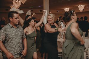 Wedding guests dancing together at a lively reception with heart decorations on the ceiling.