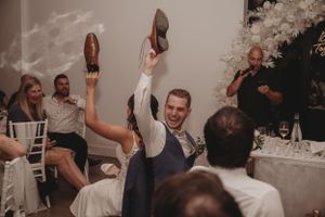 Wedding guests hold up shoes during a reception celebration.
