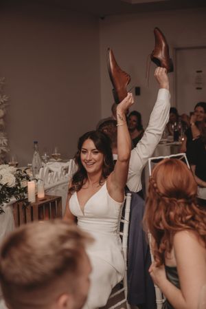 Wedding celebration with guests holding up shoes in a festive reception moment.
