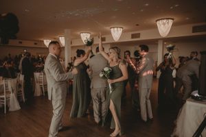 Wedding reception dance floor filled with guests dancing under vintage pendant lights.