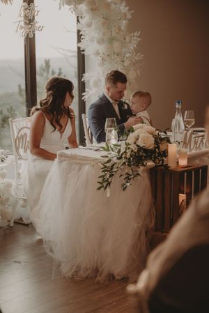 An elegant wedding reception table decorated with white florals and candlelight.