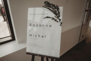 Minimalist wedding invitation design with botanical elements displayed on white easel.