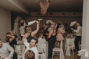Wedding reception guests hold shoes in the air during a celebratory moment.