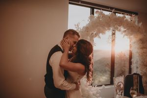 Intimate wedding moment captured during sunset with romantic lighting and floral decor.