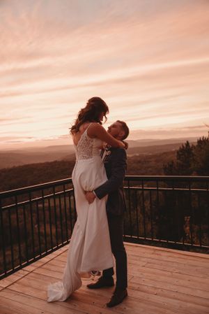 Newlyweds share an intimate dance on a mountain overlook at sunset.