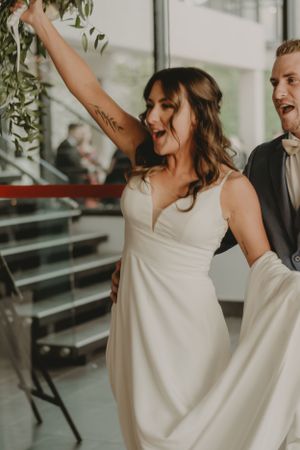 A joyful celebration at a wedding with dancing and decorative greenery in an indoor venue.
