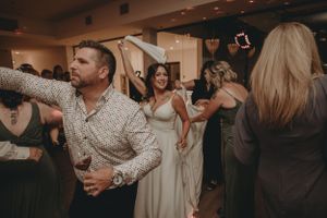 Guests dance energetically at a wedding reception under romantic lighting and decorations.