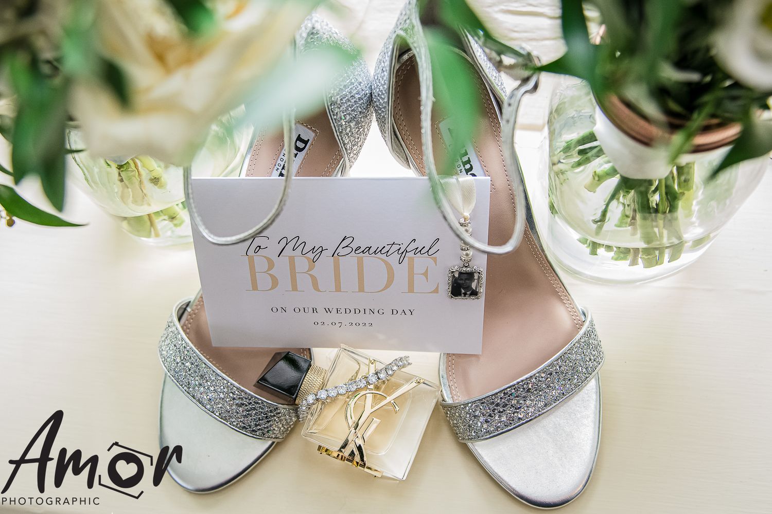 Elegant silver glitter wedding shoes next to a white invitation card.
