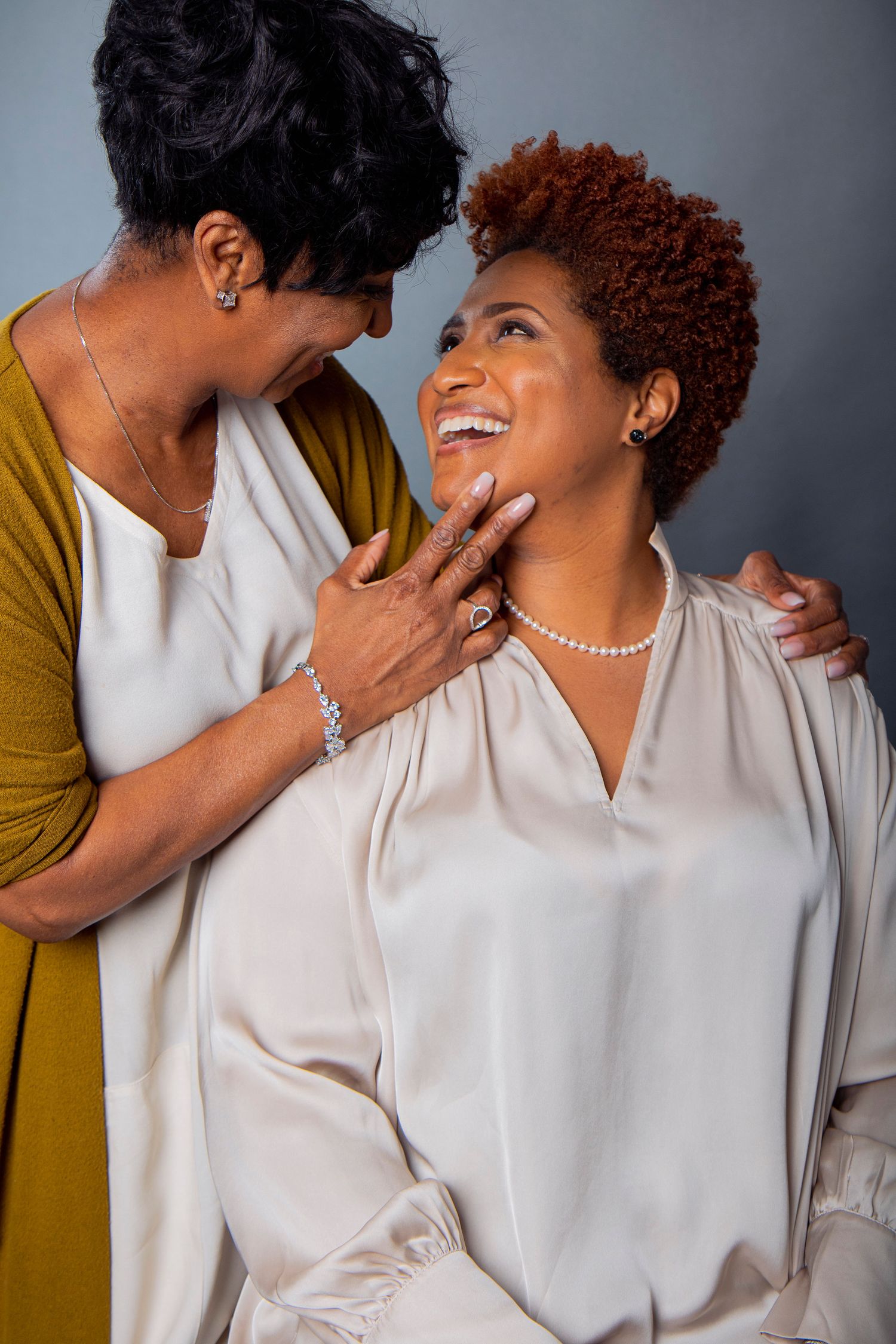 Two people share an intimate moment of joy and laughter in a studio portrait setting.