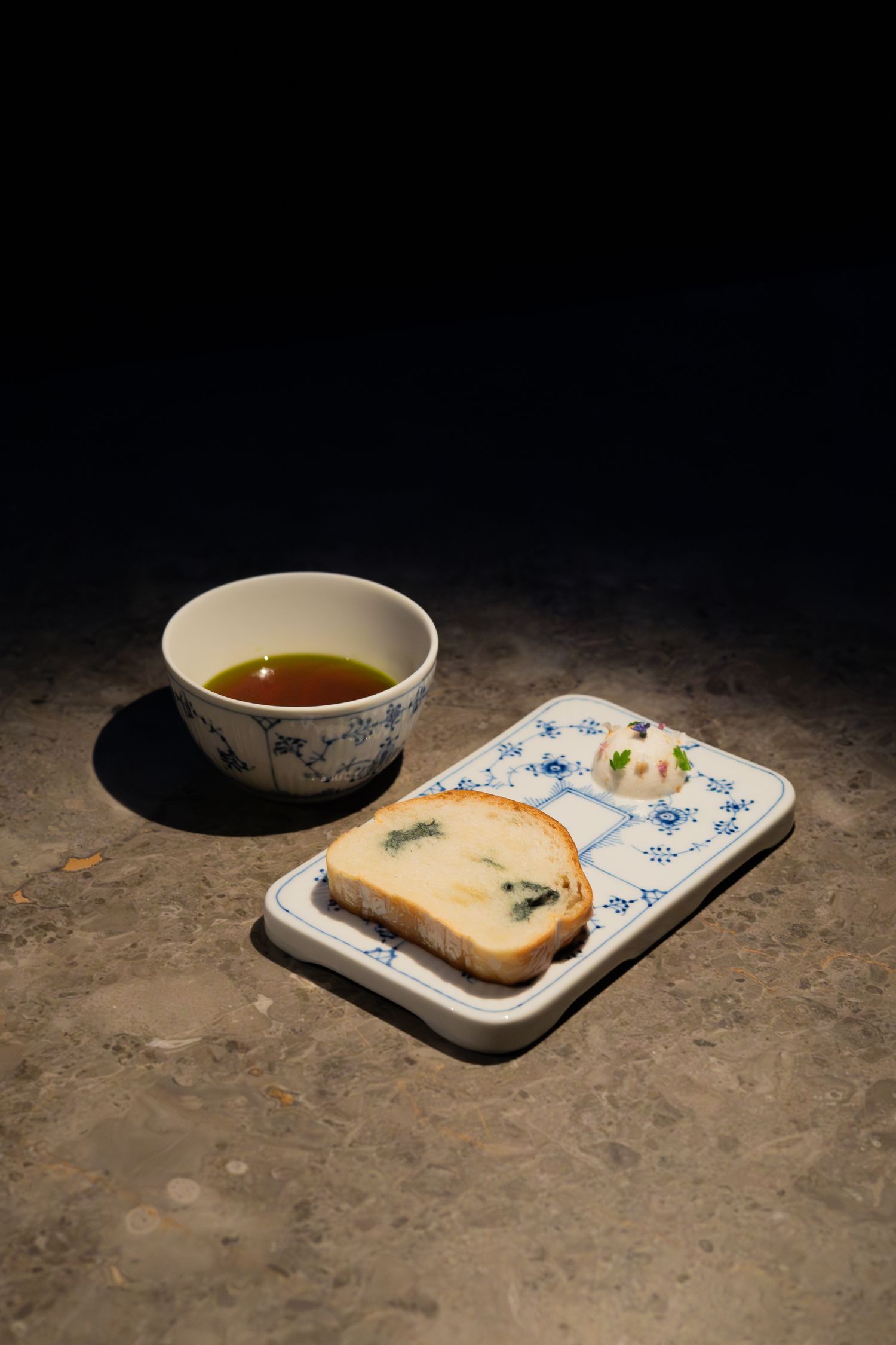 Tea and toast arrangement on blue and white china against dark textured surface.