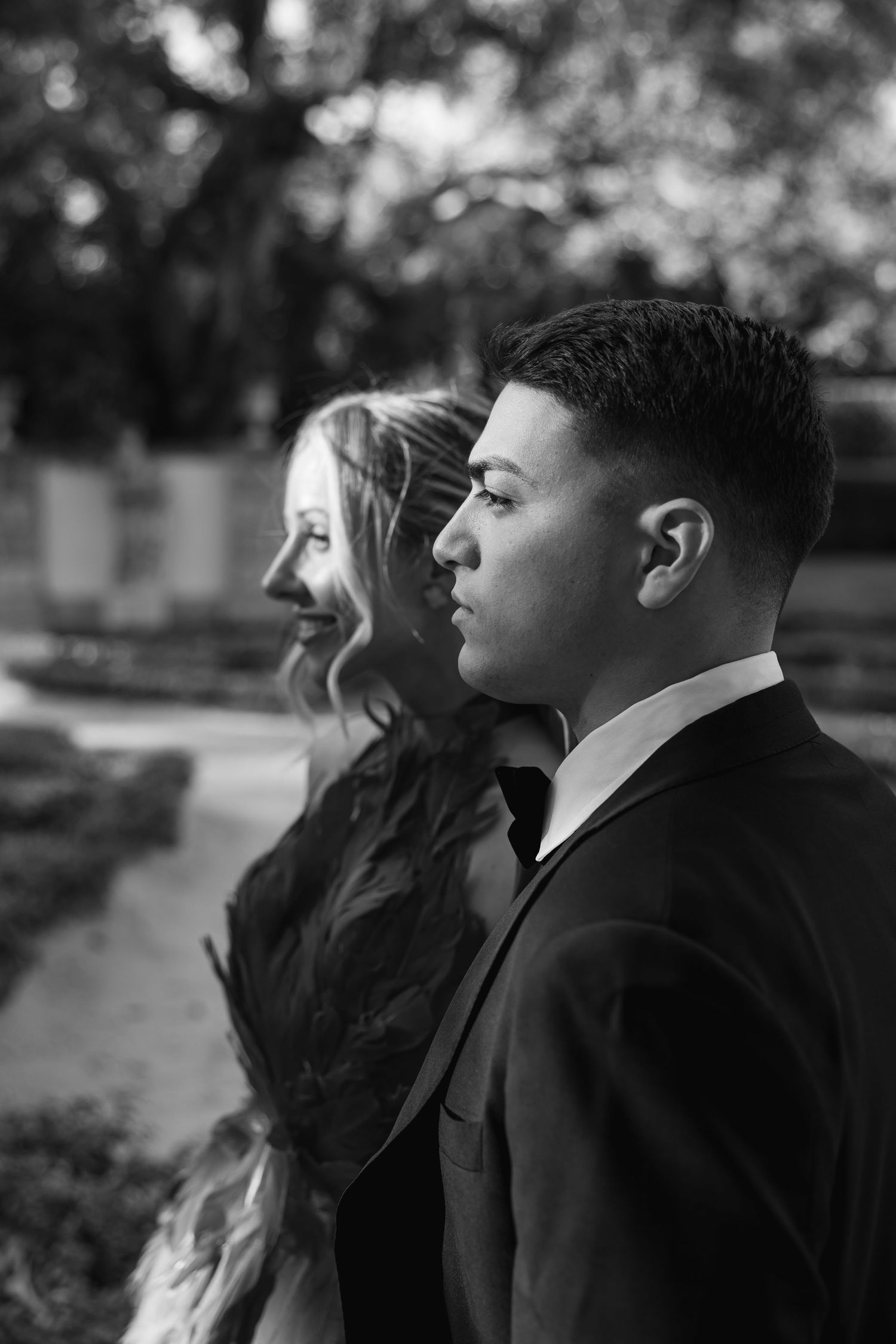 Dramatic black and white profile portrait in formal attire.