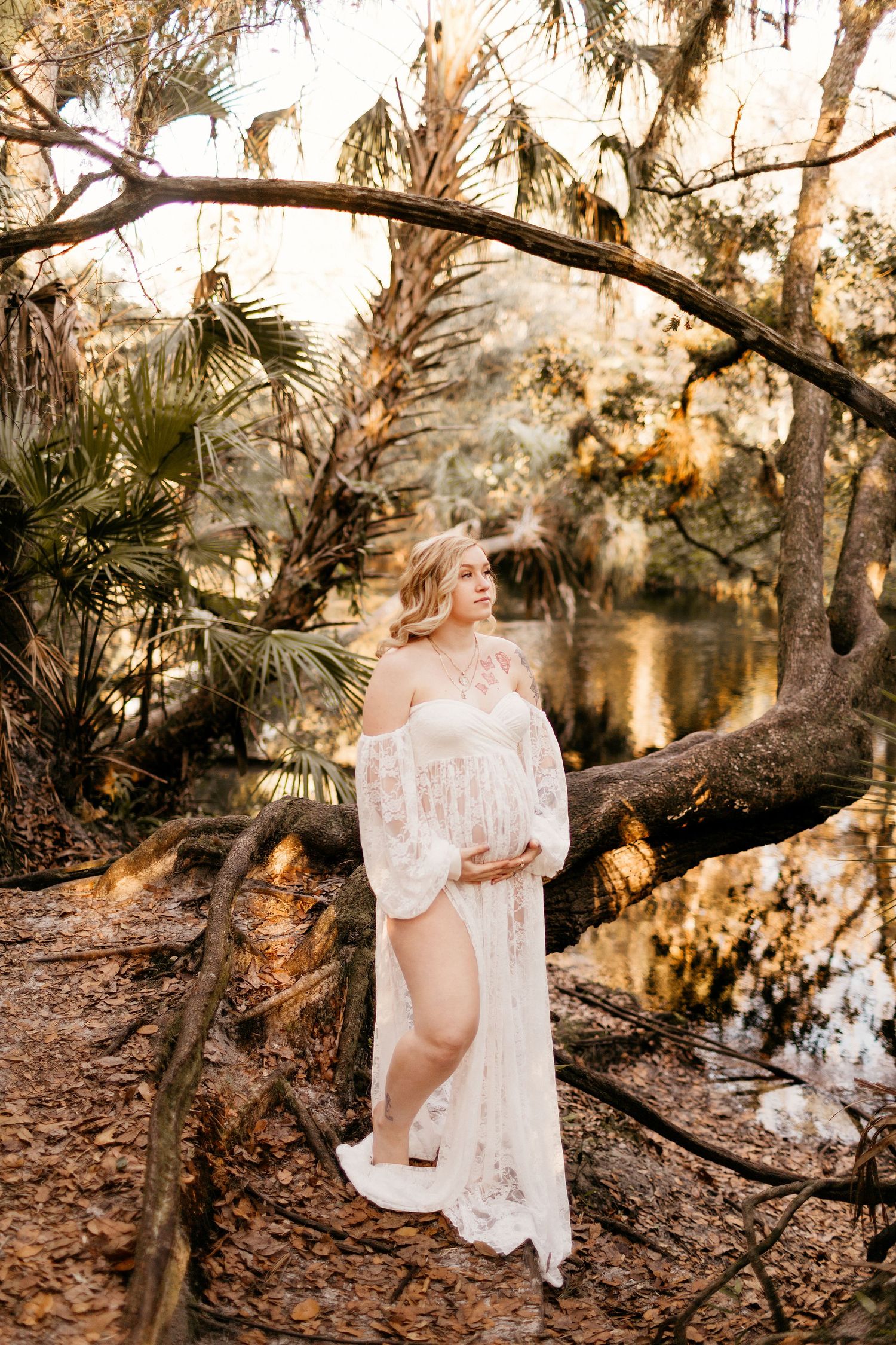 a pregnant mom is holding her belly and looking to the side while posing for a photo